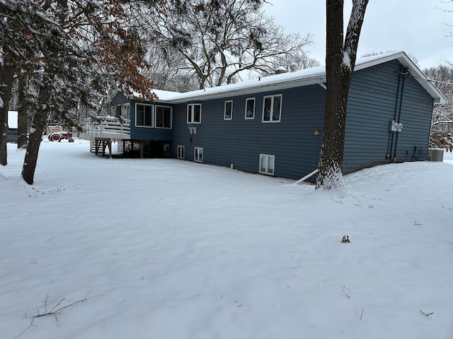 snow covered back of property with a wooden deck and central air condition unit