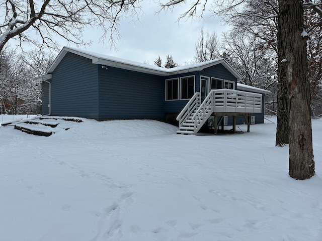 snow covered back of property featuring a wooden deck