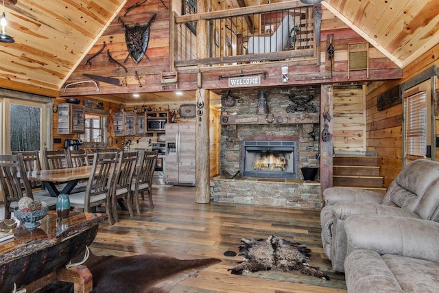 living room featuring wood-type flooring, wood ceiling, wood walls, high vaulted ceiling, and a fireplace