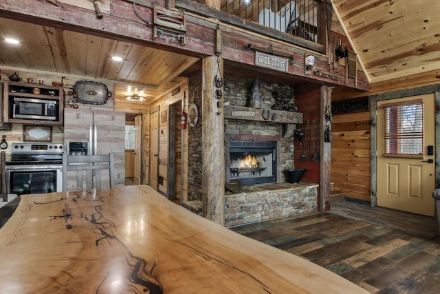 kitchen with dark hardwood / wood-style flooring, wood ceiling, wood walls, a fireplace, and appliances with stainless steel finishes