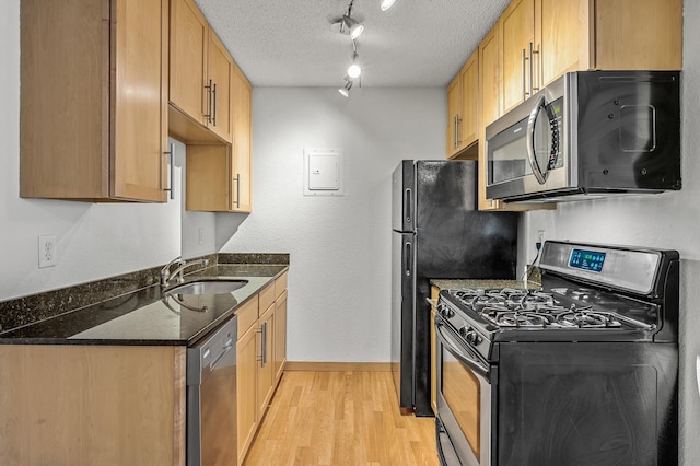 kitchen featuring light hardwood / wood-style floors, track lighting, a textured ceiling, sink, and appliances with stainless steel finishes