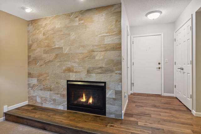 interior space with a fireplace, a textured ceiling, and dark wood-type flooring