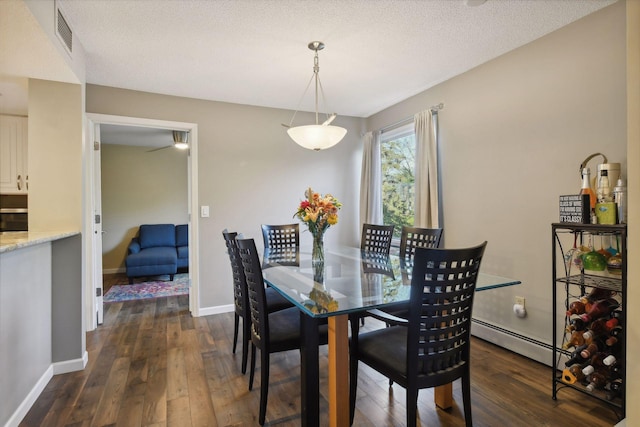 dining space with dark hardwood / wood-style flooring, a textured ceiling, and baseboard heating