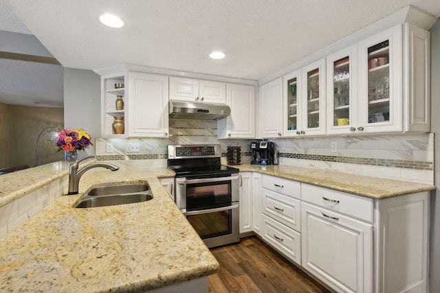 kitchen with sink, tasteful backsplash, light stone countertops, white cabinets, and range with two ovens