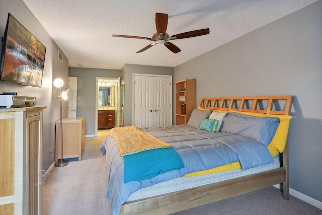 carpeted bedroom with ceiling fan, connected bathroom, a textured ceiling, and a closet