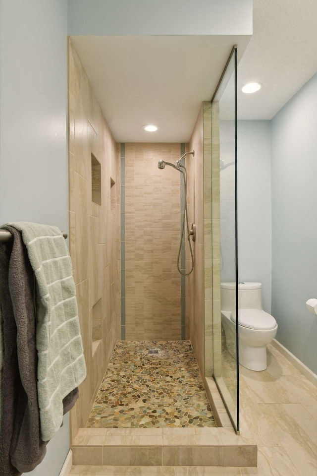 bathroom with tiled shower and toilet