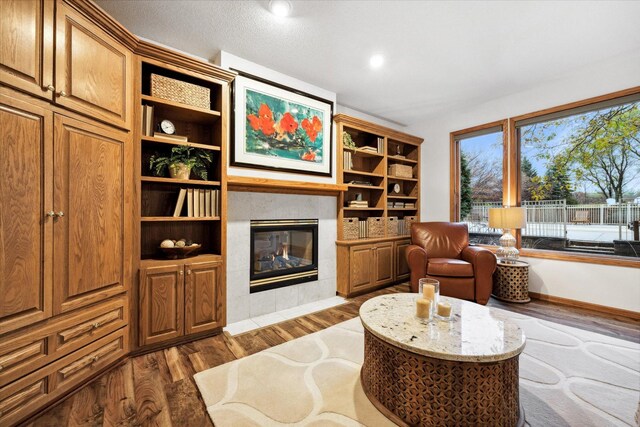 sitting room with a tiled fireplace and dark hardwood / wood-style flooring