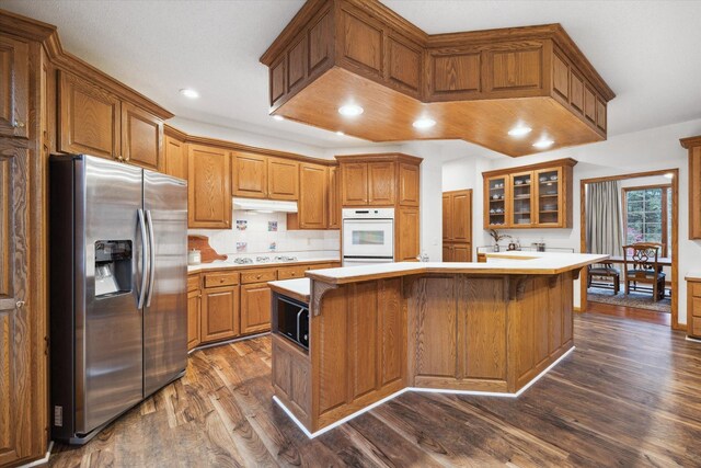 kitchen featuring a breakfast bar, dark wood-type flooring, white appliances, and a kitchen island