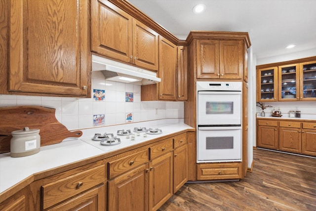 kitchen with dark hardwood / wood-style flooring, tasteful backsplash, and white appliances