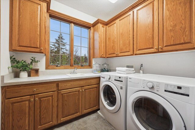 washroom with light tile patterned flooring, a textured ceiling, cabinets, sink, and washer and dryer