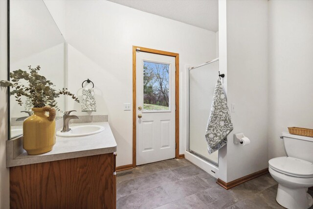 bathroom featuring toilet, vanity, and a shower with door