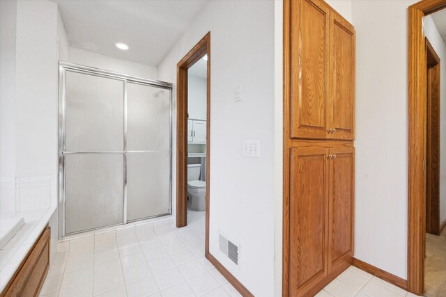 bathroom with walk in shower, tile patterned flooring, and toilet