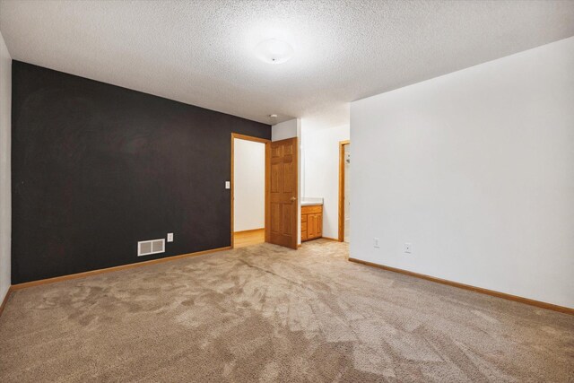 unfurnished room featuring a textured ceiling and light carpet