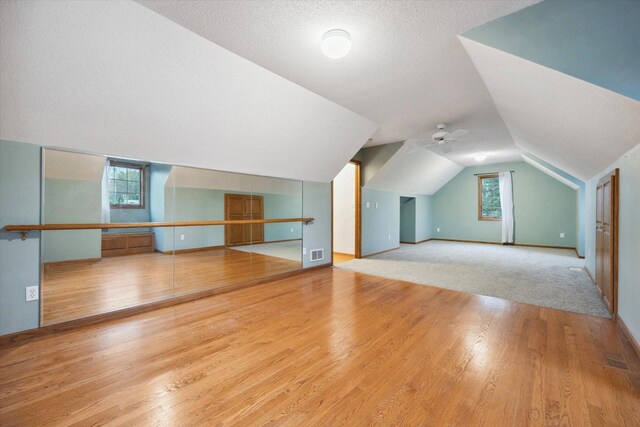 additional living space featuring a textured ceiling, light wood-type flooring, and lofted ceiling