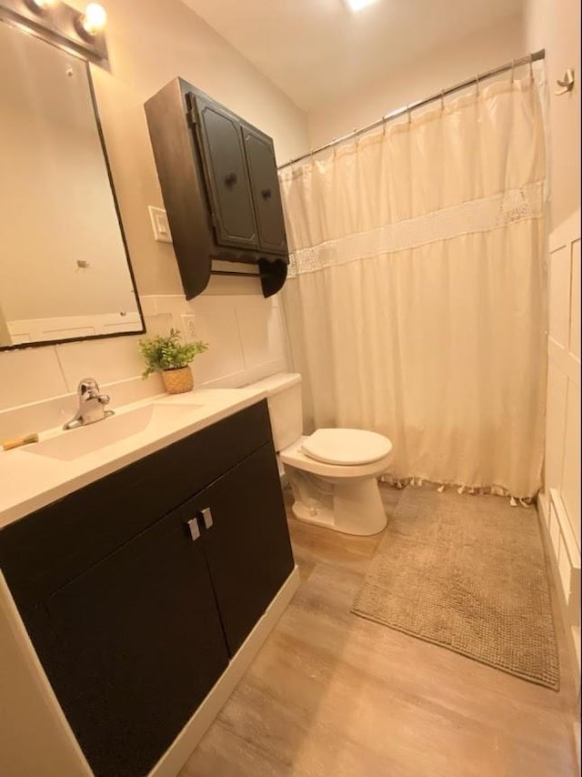 bathroom with hardwood / wood-style floors, curtained shower, vanity, and toilet