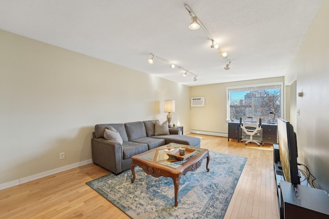 living area with a wall unit AC, light wood finished floors, baseboards, and a baseboard heating unit