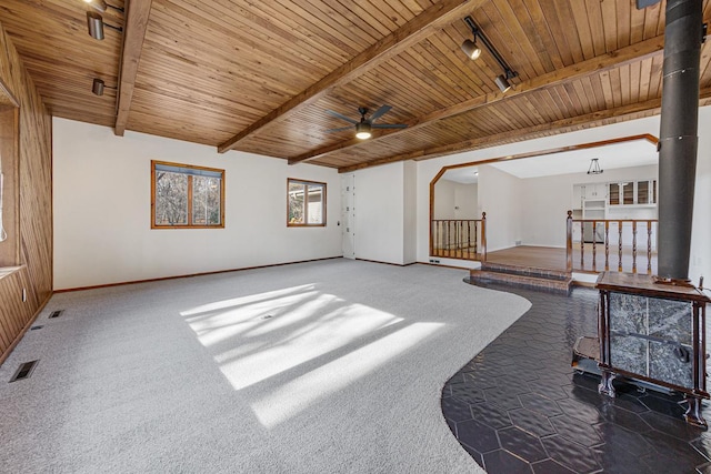 living room featuring a wood stove, wooden ceiling, rail lighting, ceiling fan, and beamed ceiling