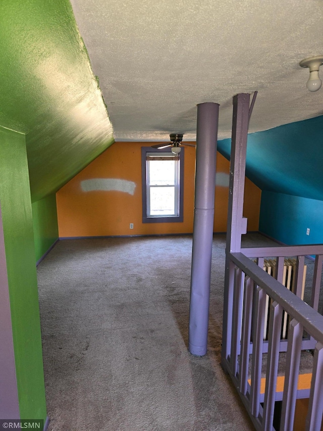 additional living space with carpet, a textured ceiling, ceiling fan, and vaulted ceiling