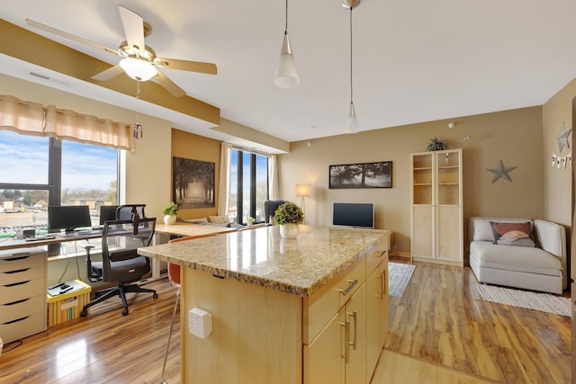 kitchen featuring light stone counters, decorative light fixtures, light hardwood / wood-style floors, a kitchen island, and a breakfast bar area