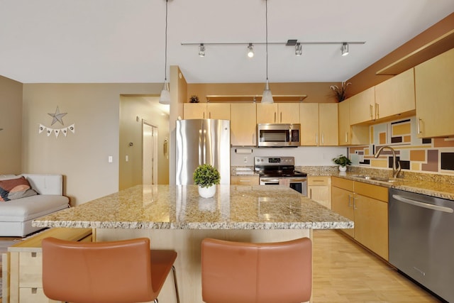 kitchen featuring pendant lighting, stainless steel appliances, a kitchen bar, and sink