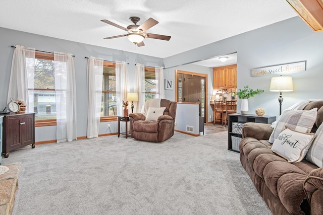 living room with ceiling fan, light carpet, and a textured ceiling