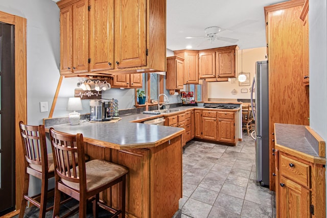 kitchen with gas cooktop, a ceiling fan, a peninsula, freestanding refrigerator, and a sink