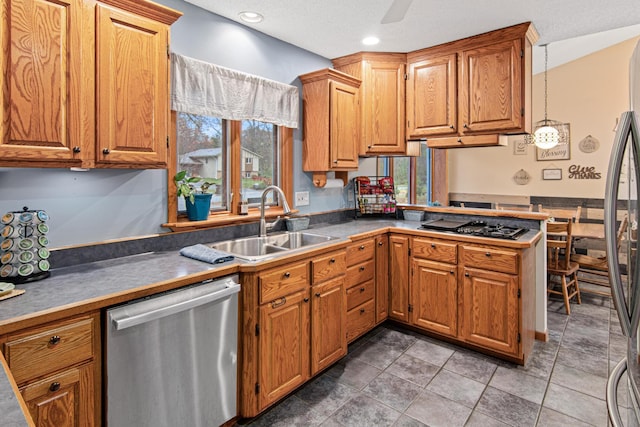 kitchen with a sink, stainless steel dishwasher, a peninsula, brown cabinetry, and black cooktop