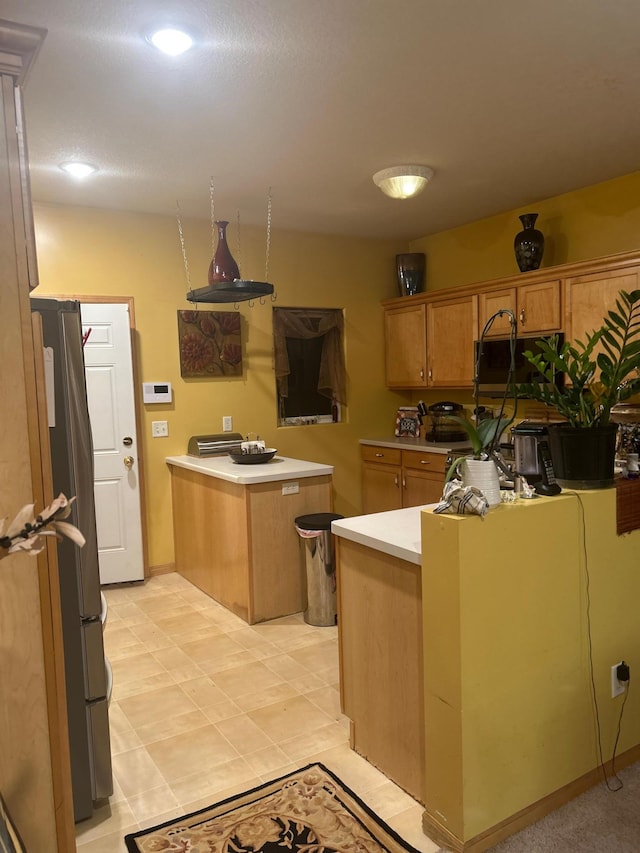 kitchen featuring kitchen peninsula, light tile patterned floors, a kitchen island, and stainless steel refrigerator