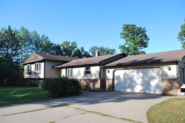 split level home featuring an attached garage, driveway, a front yard, and brick siding