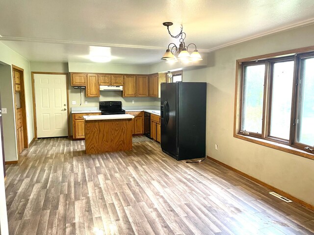 12303 71st Ave SW, Motley, MN 56466 - kitchen with black appliances, under cabinet range hood, light countertops, brown cabinets, and baseboards