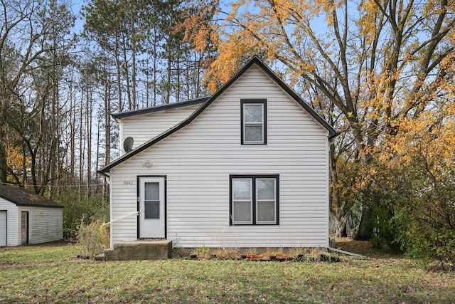 back of house with a yard and a storage shed