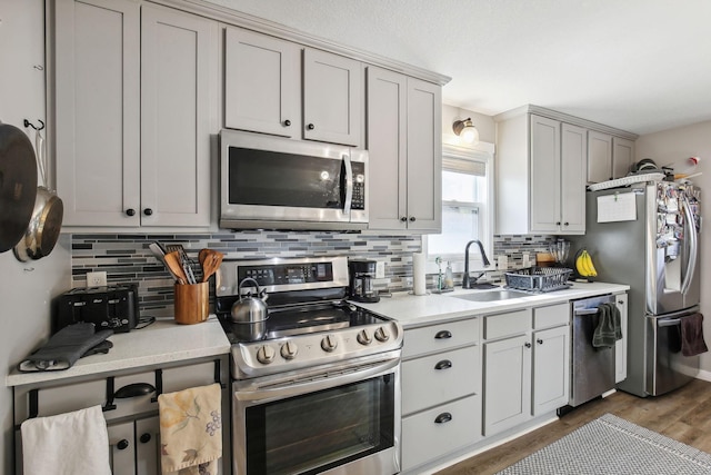 kitchen with dark wood-type flooring, backsplash, sink, and stainless steel appliances