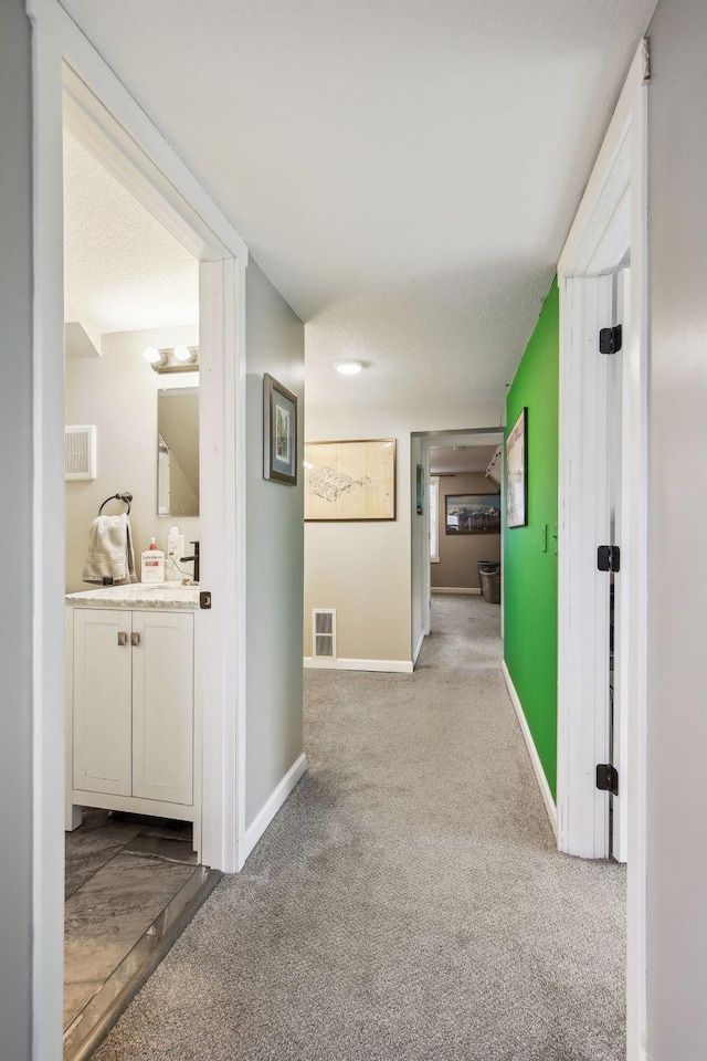 hall with sink and light carpet