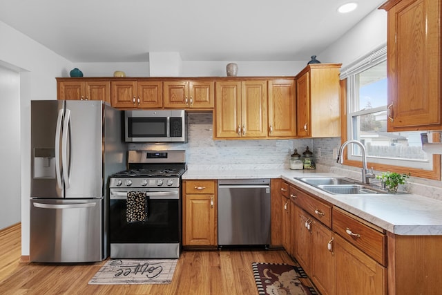 4425 2nd St NE, Columbia Heights, MN 55421 - kitchen featuring stainless steel appliances, a sink, light countertops, light wood finished floors, and tasteful backsplash