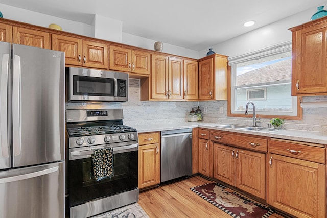 kitchen with sink, backsplash, appliances with stainless steel finishes, and light hardwood / wood-style flooring