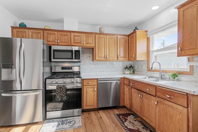 4425 2nd St NE, Columbia Heights, MN 55421 - kitchen featuring stainless steel appliances, a sink, light countertops, decorative backsplash, and light wood-type flooring