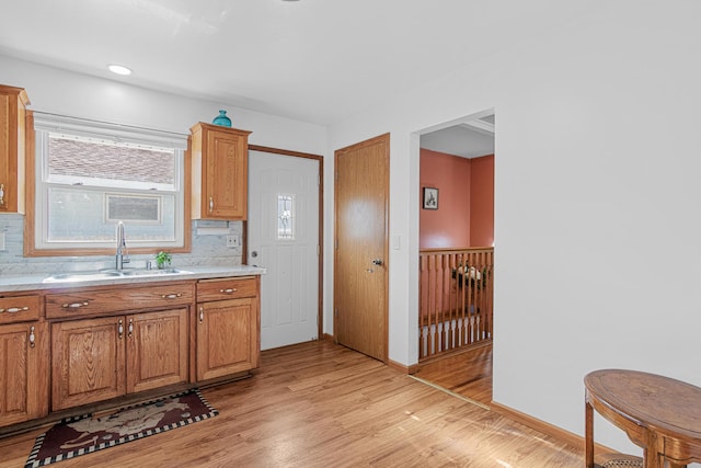 4425 2nd St NE, Columbia Heights, MN 55421 - kitchen featuring a sink, light countertops, light wood-style floors, decorative backsplash, and brown cabinets
