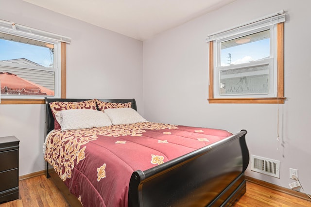 bedroom with hardwood / wood-style flooring and multiple windows