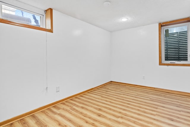 basement with a textured ceiling and light hardwood / wood-style flooring