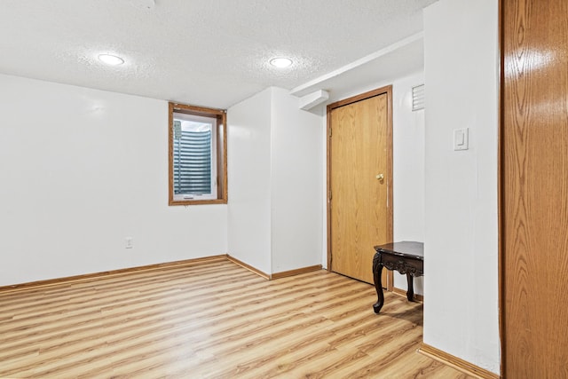 empty room featuring light wood-type flooring and a textured ceiling