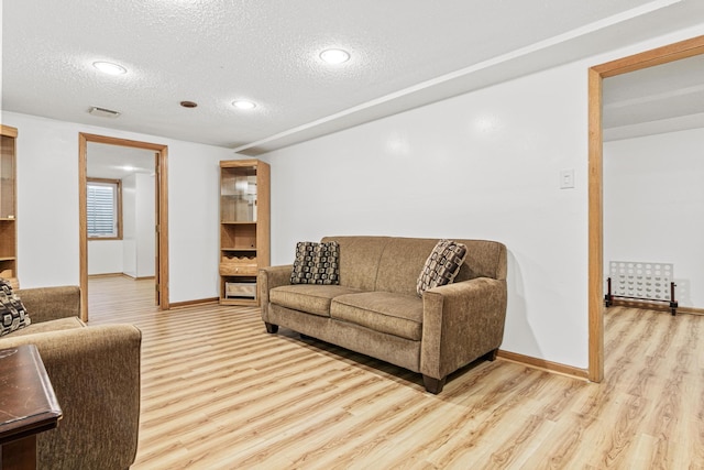 living room featuring light hardwood / wood-style floors and a textured ceiling