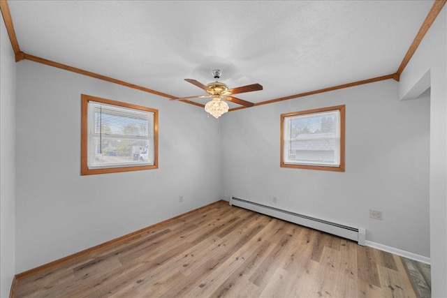 empty room with a healthy amount of sunlight, light hardwood / wood-style floors, ornamental molding, and a baseboard heating unit