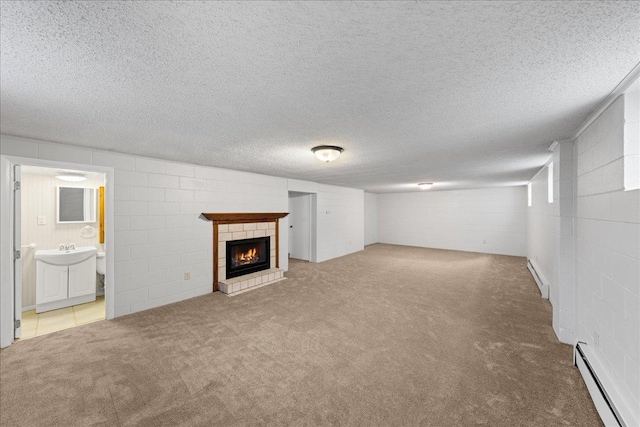 basement featuring carpet, a textured ceiling, a tile fireplace, and a baseboard radiator