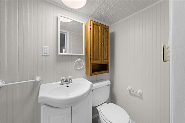 bathroom with wooden walls, sink, and toilet