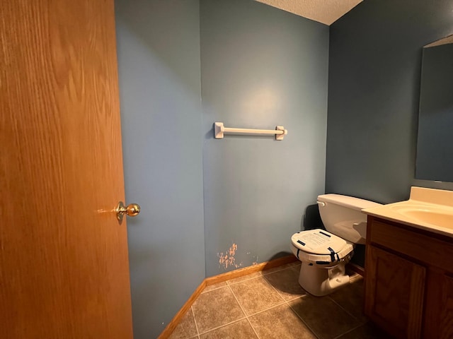 bathroom with toilet, vanity, a textured ceiling, and tile patterned floors