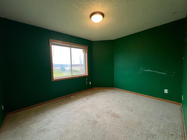 carpeted empty room featuring a textured ceiling