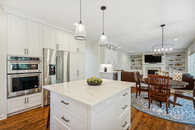 kitchen featuring open floor plan, stainless steel appliances, dark wood-style flooring, and a fireplace