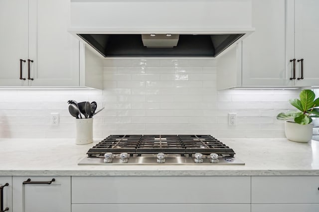 kitchen featuring tasteful backsplash, white cabinetry, stainless steel gas stovetop, and exhaust hood