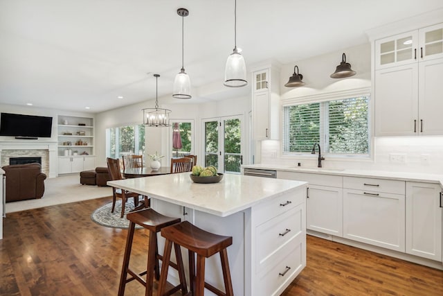 kitchen featuring white cabinets, a sink, a stone fireplace, and a kitchen breakfast bar