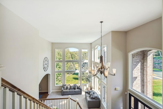 interior space featuring arched walkways, carpet flooring, baseboards, and an inviting chandelier